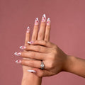 Starlet press-on nails, pink and white French tips with magenta sparkle stars, two hands on a rose backdrop