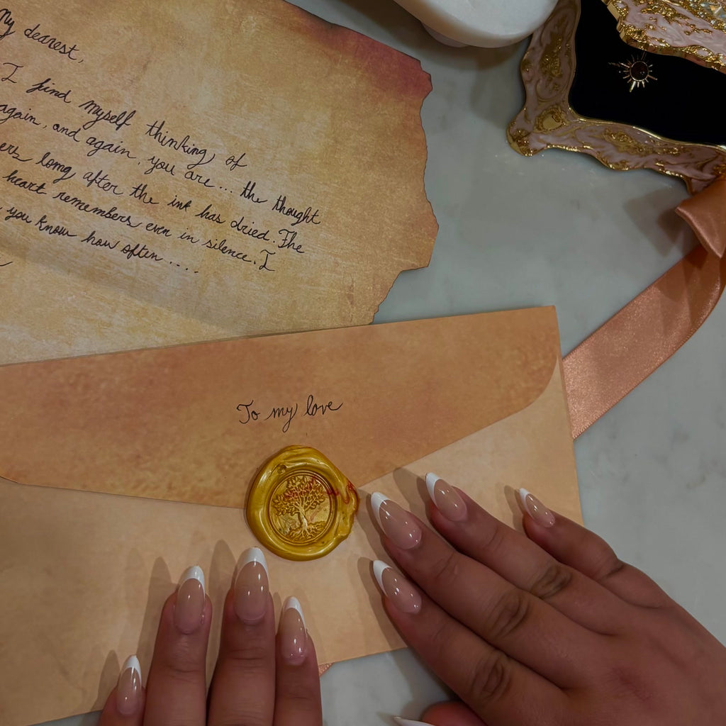 White Tip press-on nails, nude almond with clean white French tips, resting on a handwritten letter and a wax sealed envelope